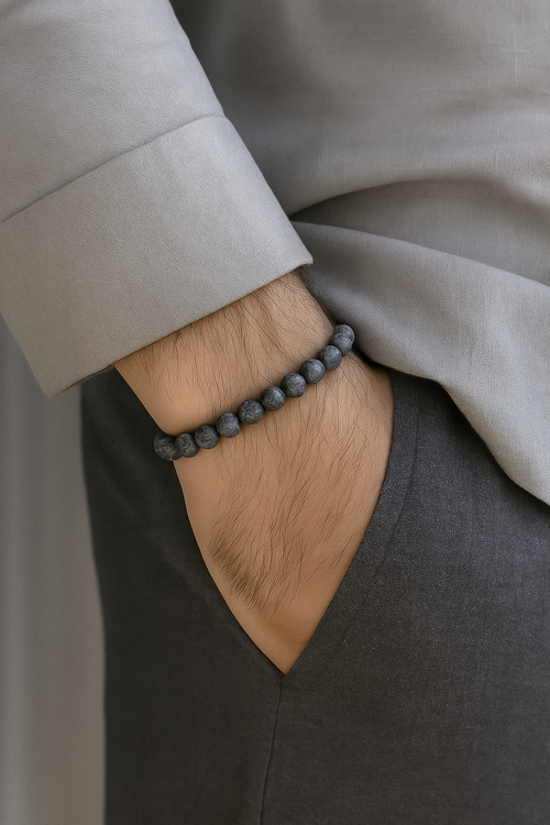 Cosmic Collections Lunar herenarmband – handgemaakte elastische grijs-zwarte natuursteen kralenarmband gedragen bij lichtgrijs overhemd en donkere pantalon